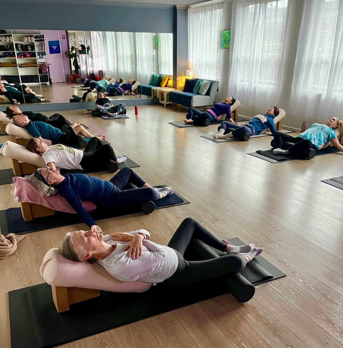 Students resting on bolsters during a restorative yoga class in Lane Cove