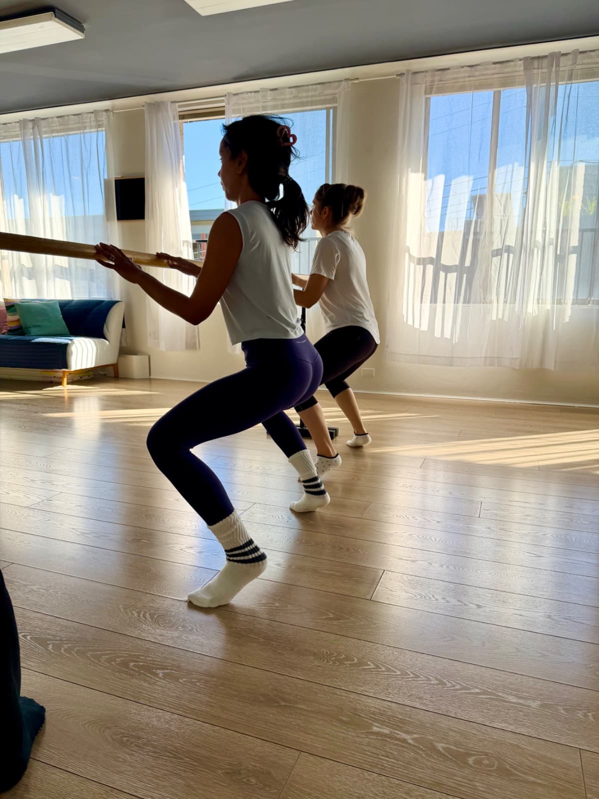 Two students doing barre squats in the sun-filled Evolvere Lane Cove studio