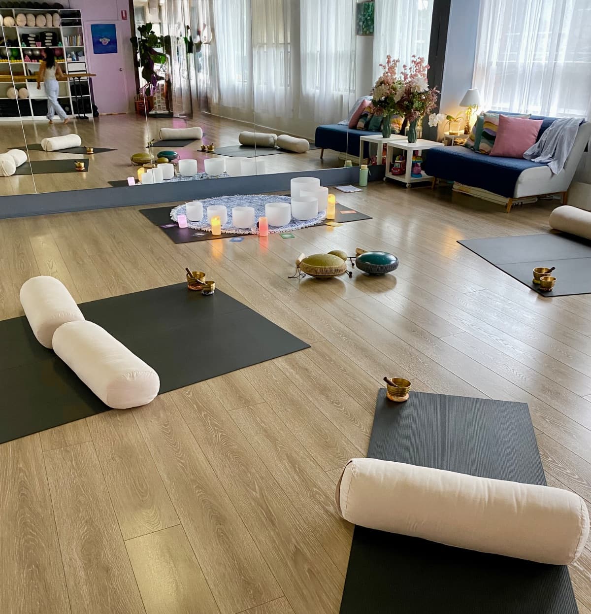 Sound bath studio set up with crystal bowls, bolsters and candles for a group session